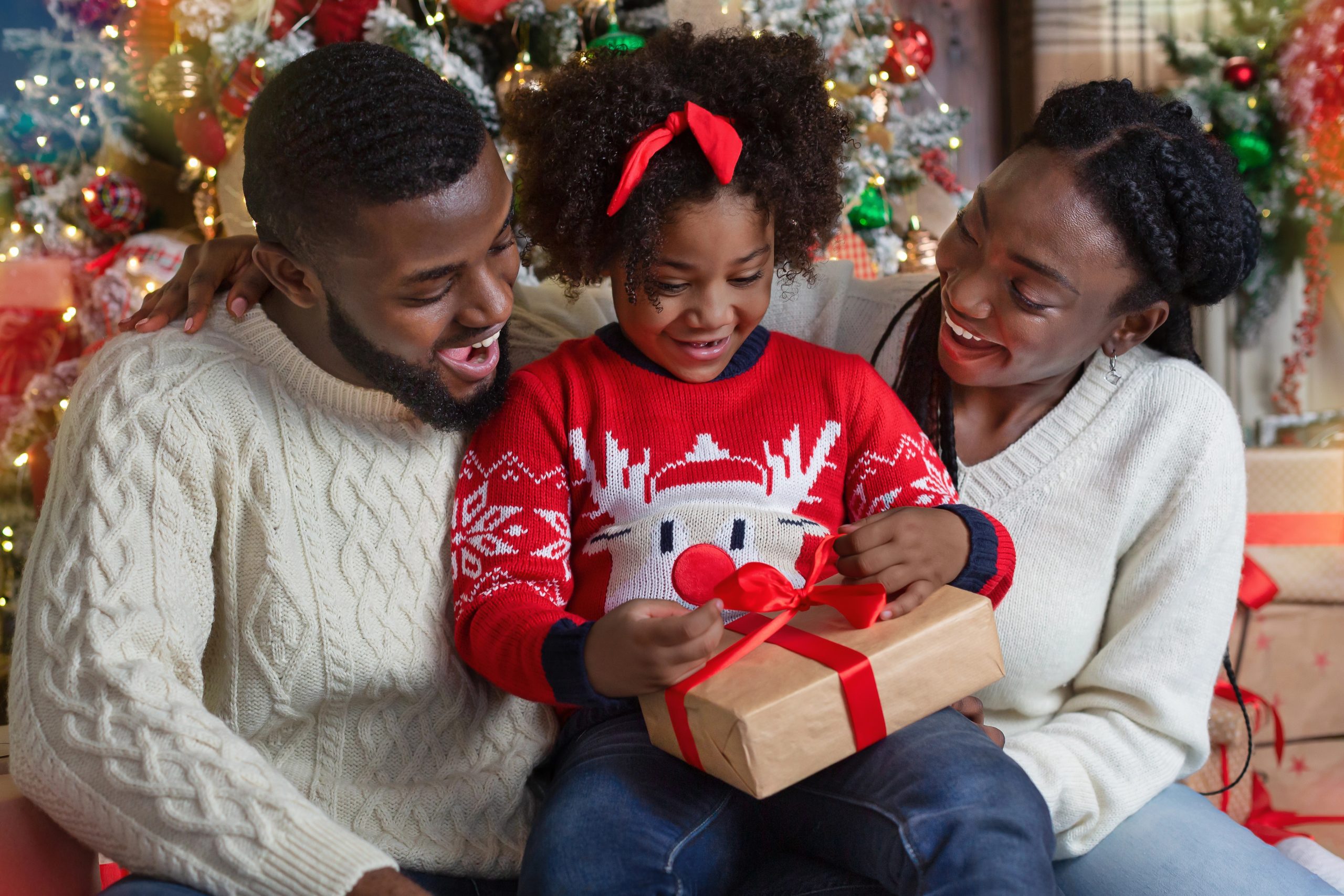 Child sitting on parents lap opening present