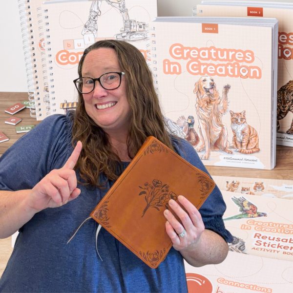 Kim Sorgius Jones holding a Bible in front of Not Consumed Creatures in Creation and Connections homeschool curriculum